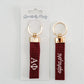 Two red keychains with white Alpha Phi Greek letters and gold rings on a white background