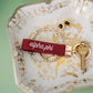 Decorative dish with red Alpha Phi embroidered keychain and jewelry.