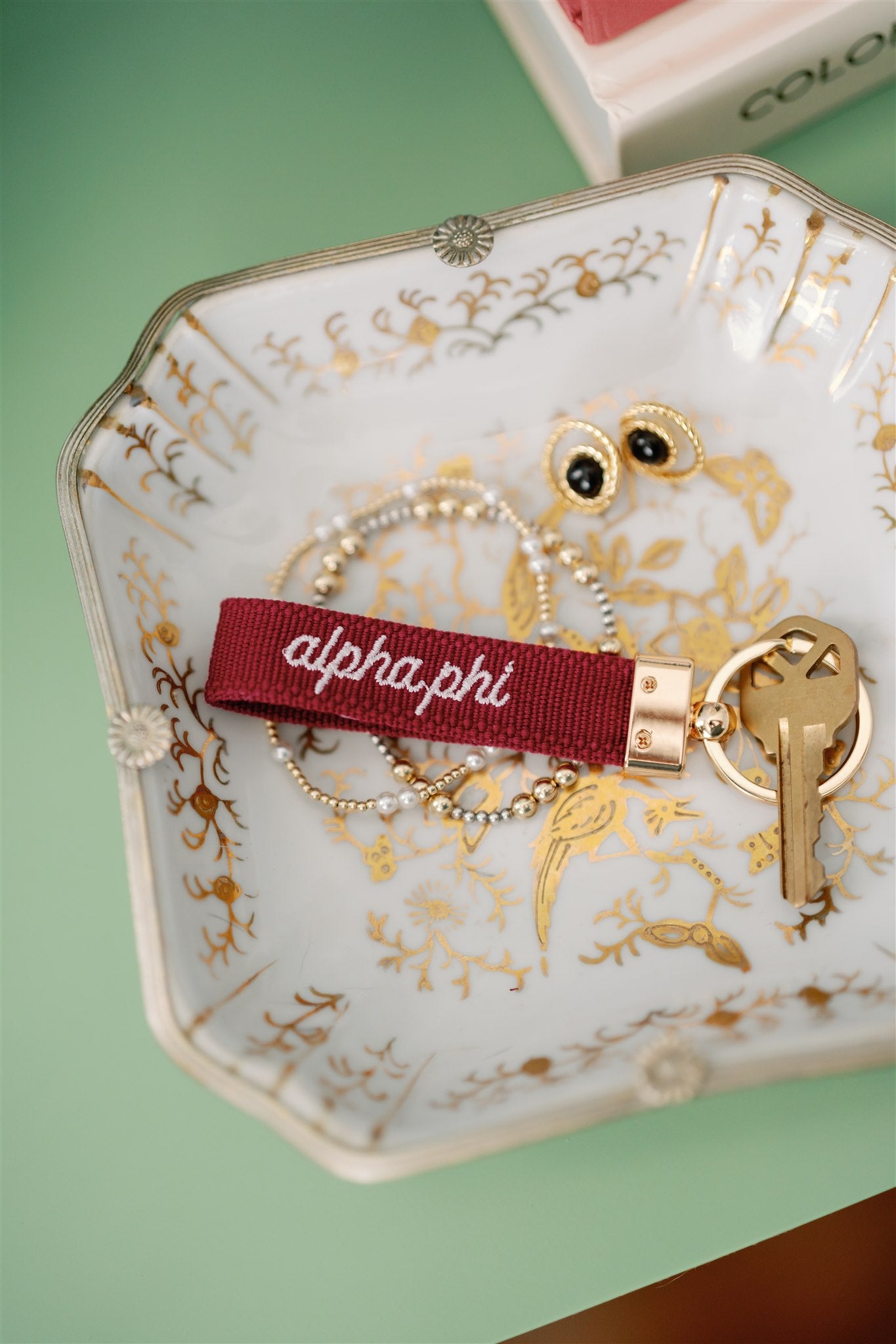 Decorative dish with red Alpha Phi embroidered keychain and jewelry.