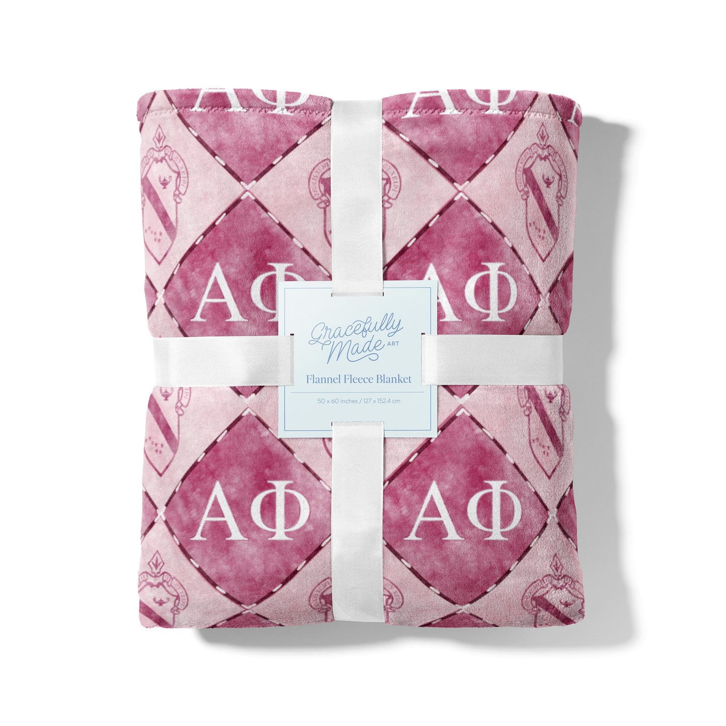 Pink patterned blanket with white ribbon and 'Gracefully Made' label on a white background