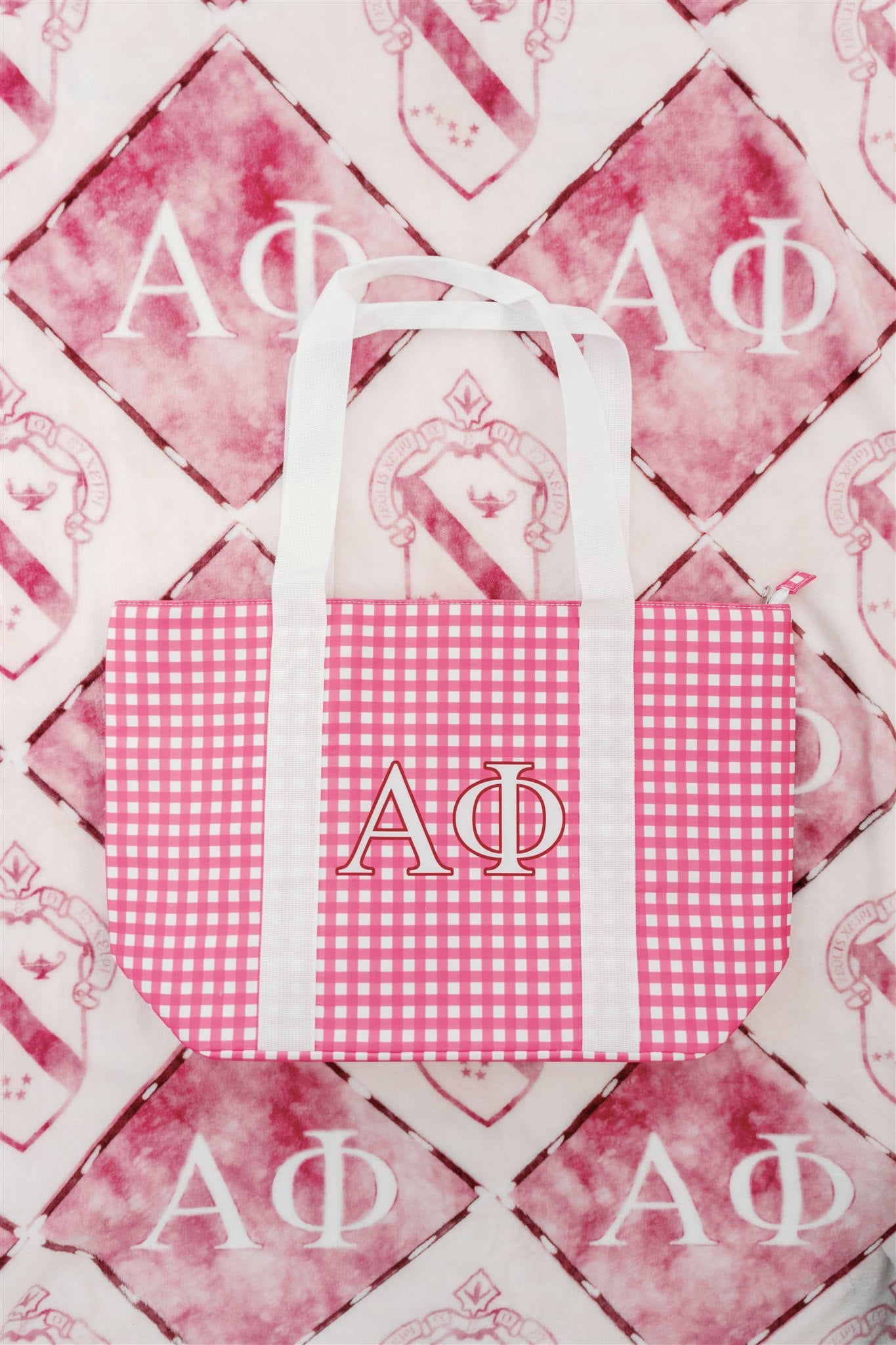 Pink gingham bag with 'ΑΦ' Greek letters on a fleece flannel blanket as the background.