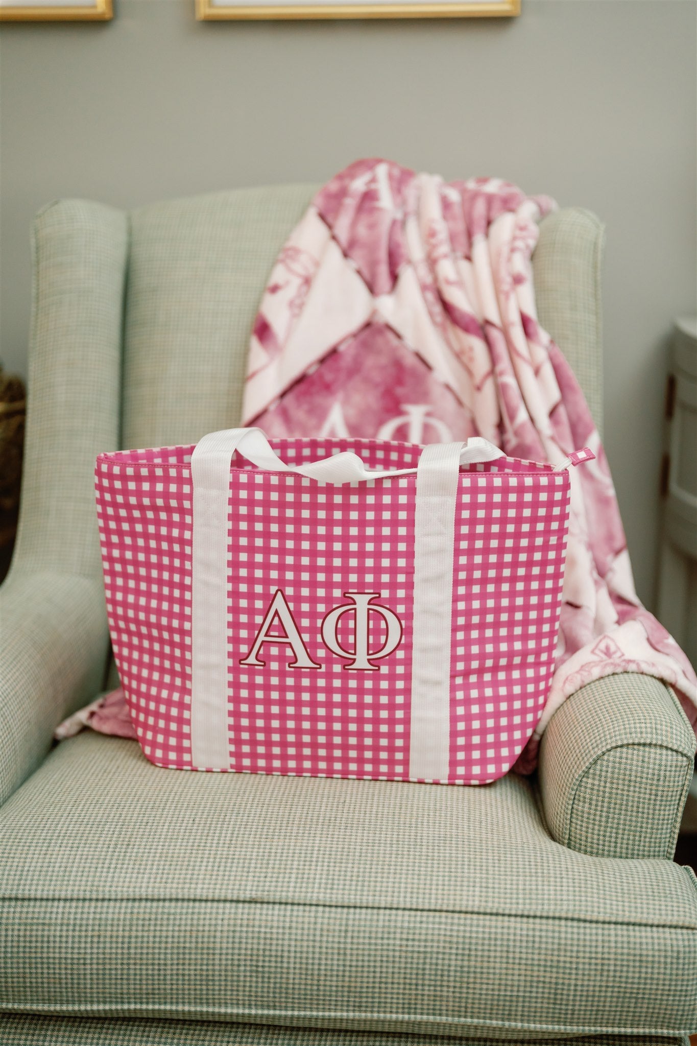 Pink gingham bag with Alpha Phi Greek letters on a green armchair