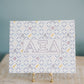 Art print with Alpha Xi Delta Greek letters on a stand against a blue background