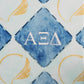 Patterned fabric with blue and gold design featuring Greek letters for Alpha Xi Delta sorority