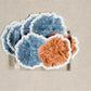 Sticker of an orange and blue pom pom.