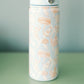 Light blue water bottle with white and orange Auburn designs on a green surface and gray background