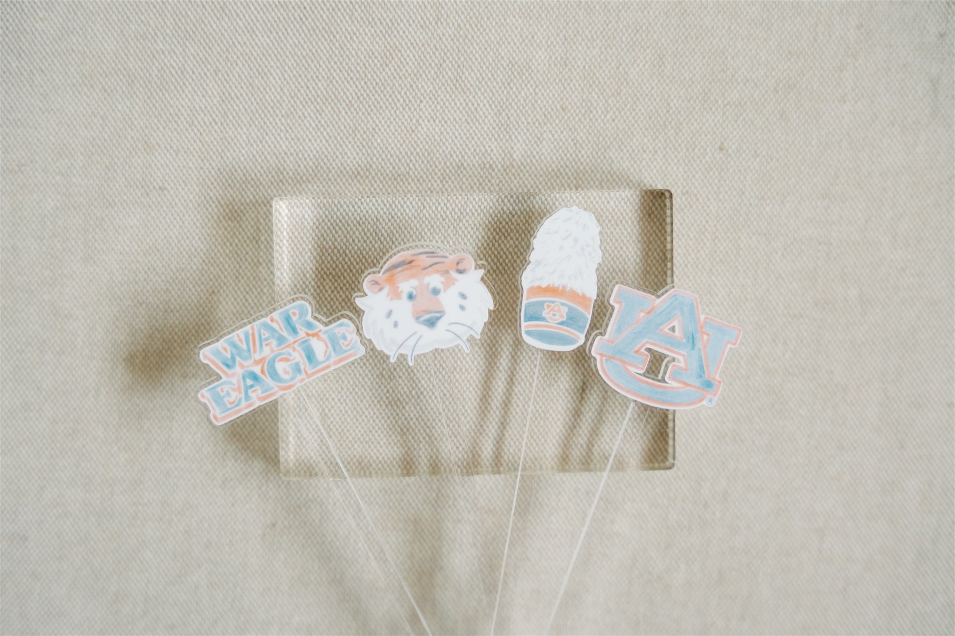 Acrylic stir sticks with watercolor Auburn University icons on the top of them.