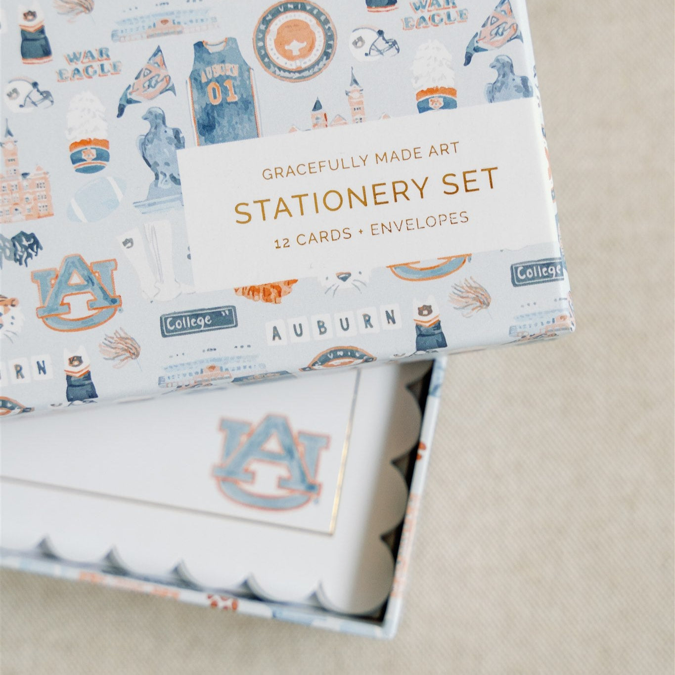 Stationery with scalloped edges, a gold rim, and a watercolor Auburn logo.