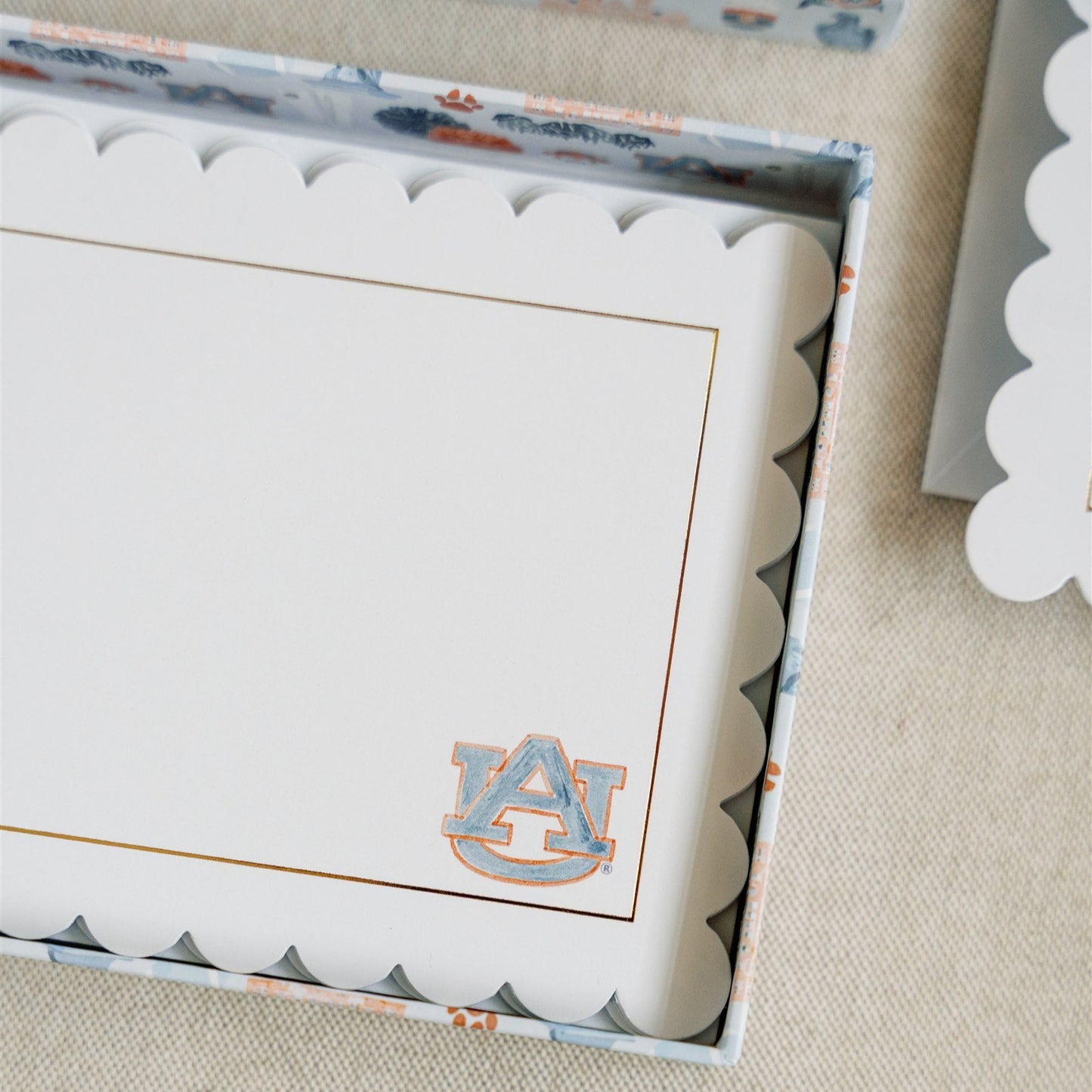 Stationery with scalloped edges, a gold rim, and a watercolor Auburn logo.