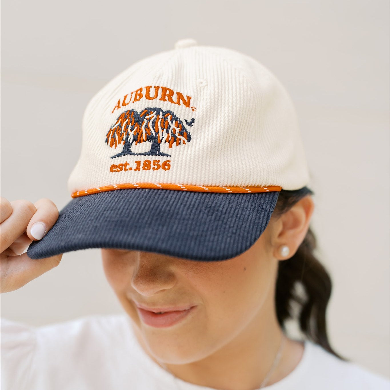 Person wearing a baseball cap with 'Auburn' and 'Est. 1856' on a plain background