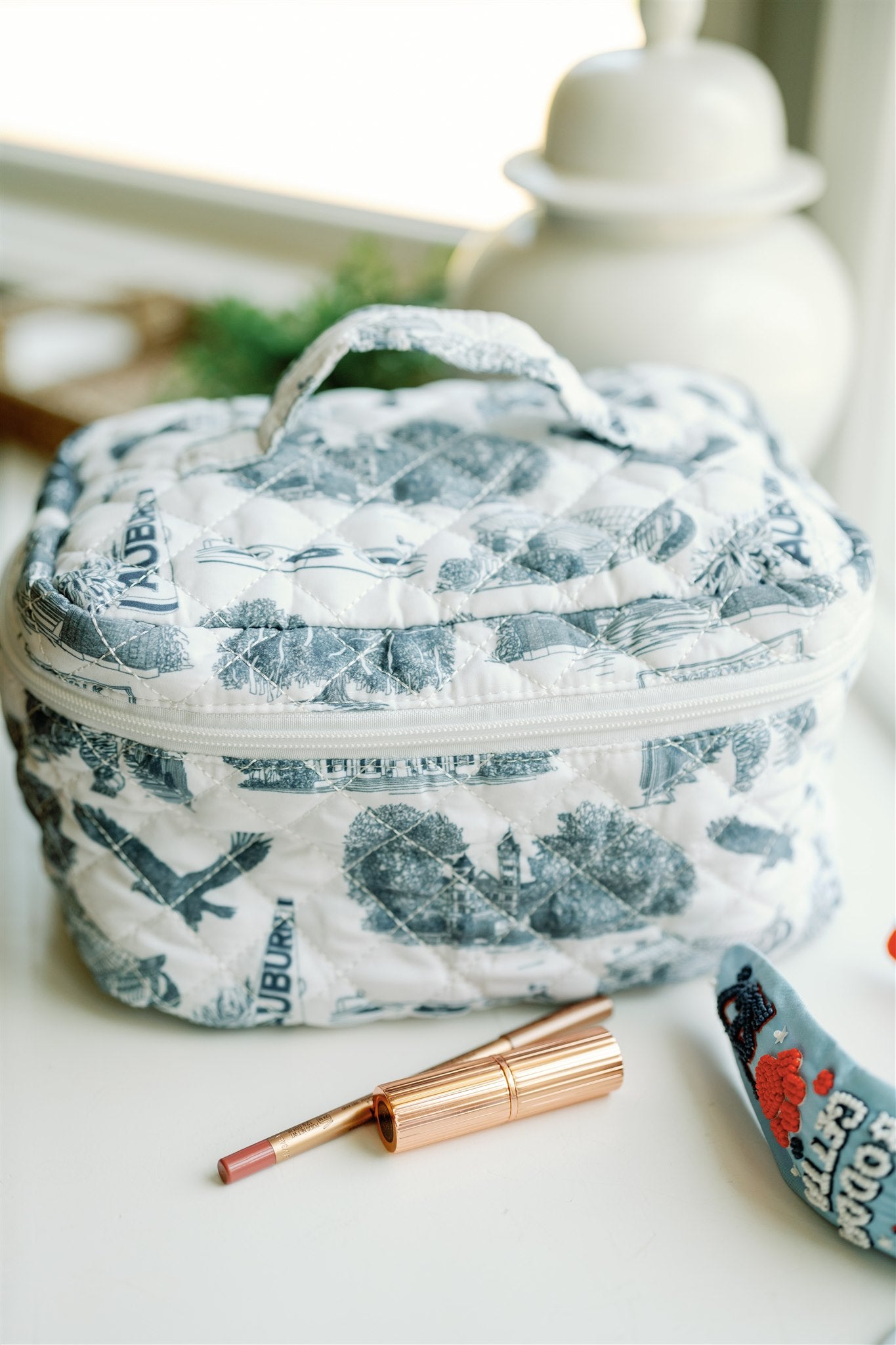 White quilted makeup bag with navy blue Auburn University symbols.
