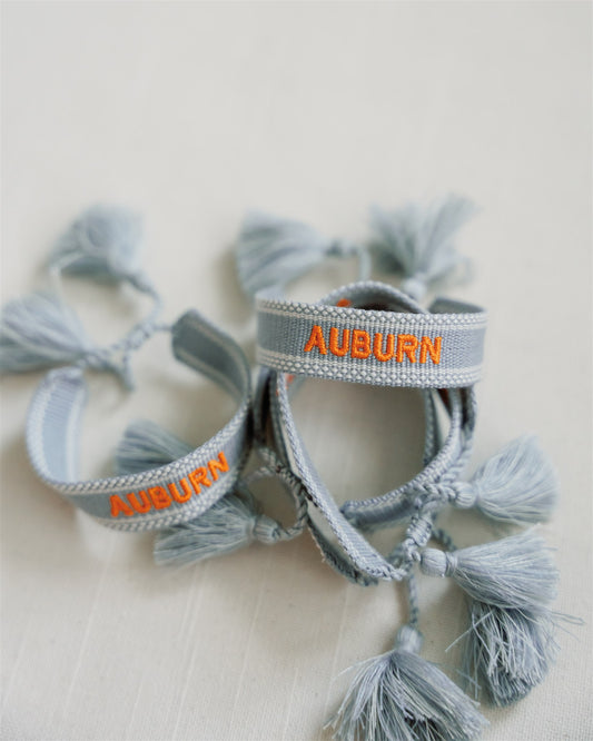 Light blue woven bracelet with "Auburn" embroidered in orange.