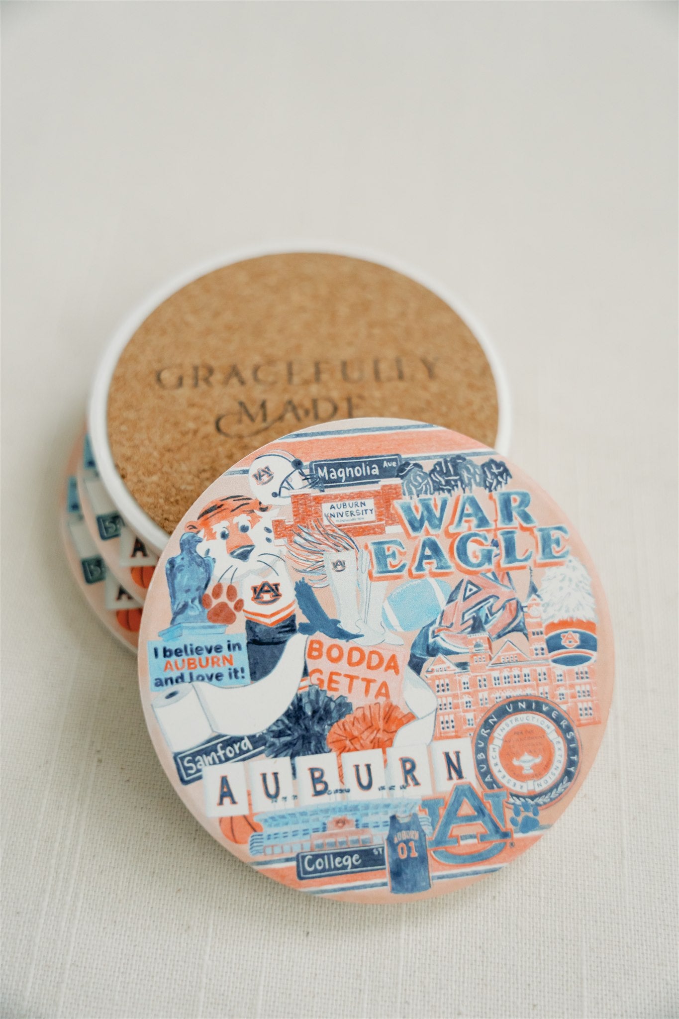 Ceramic coasters with a collage of watercolor illustrations of Auburn University landmarks and icons.