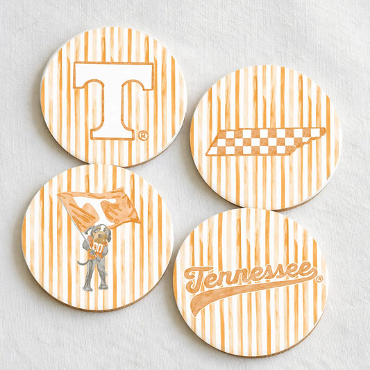 Orange and white striped coasters with Tennessee icons on them laying on a grey background.