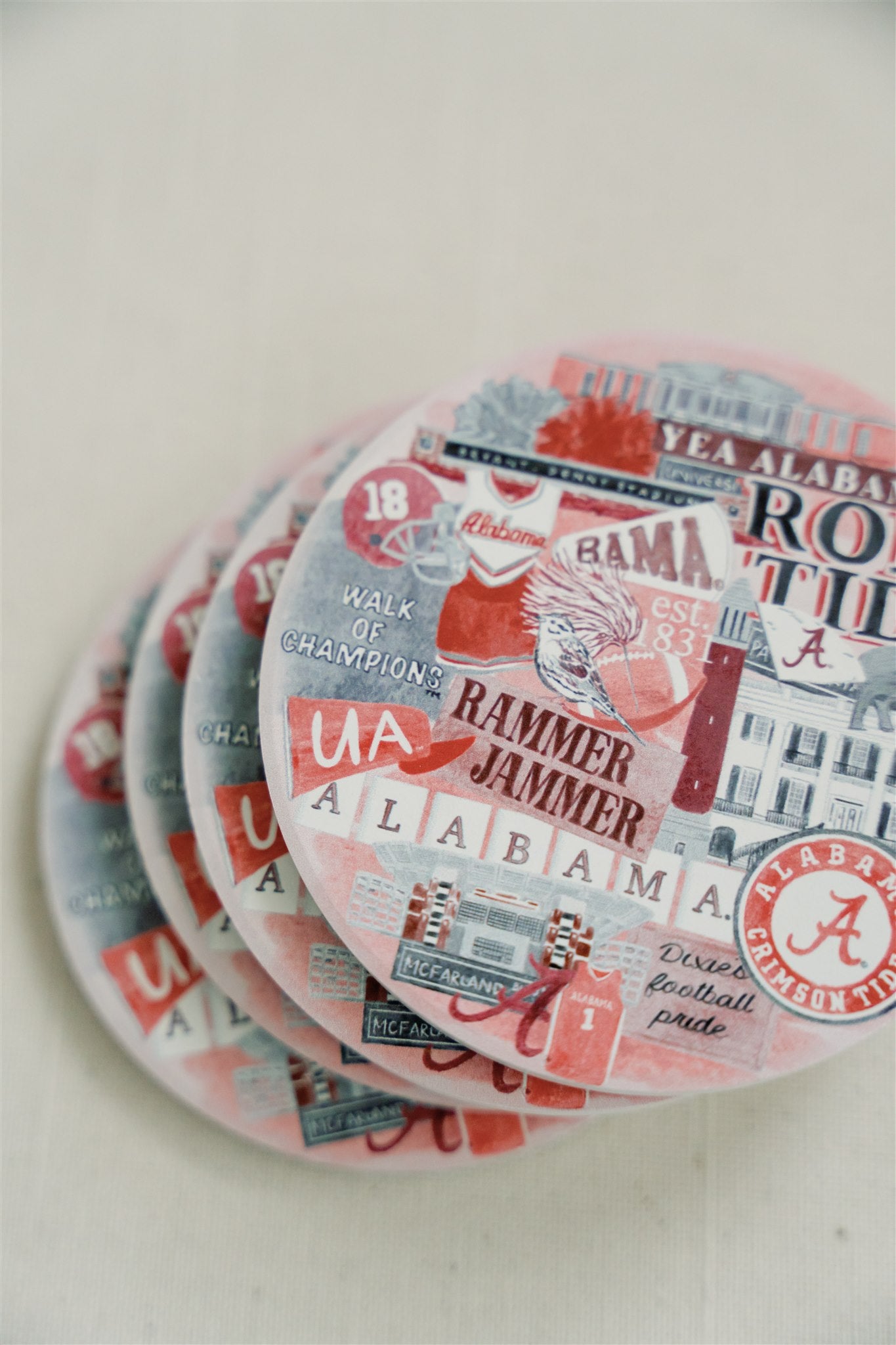 Ceramic coasters featuring a collage of watercolor University of Alabama symbols.