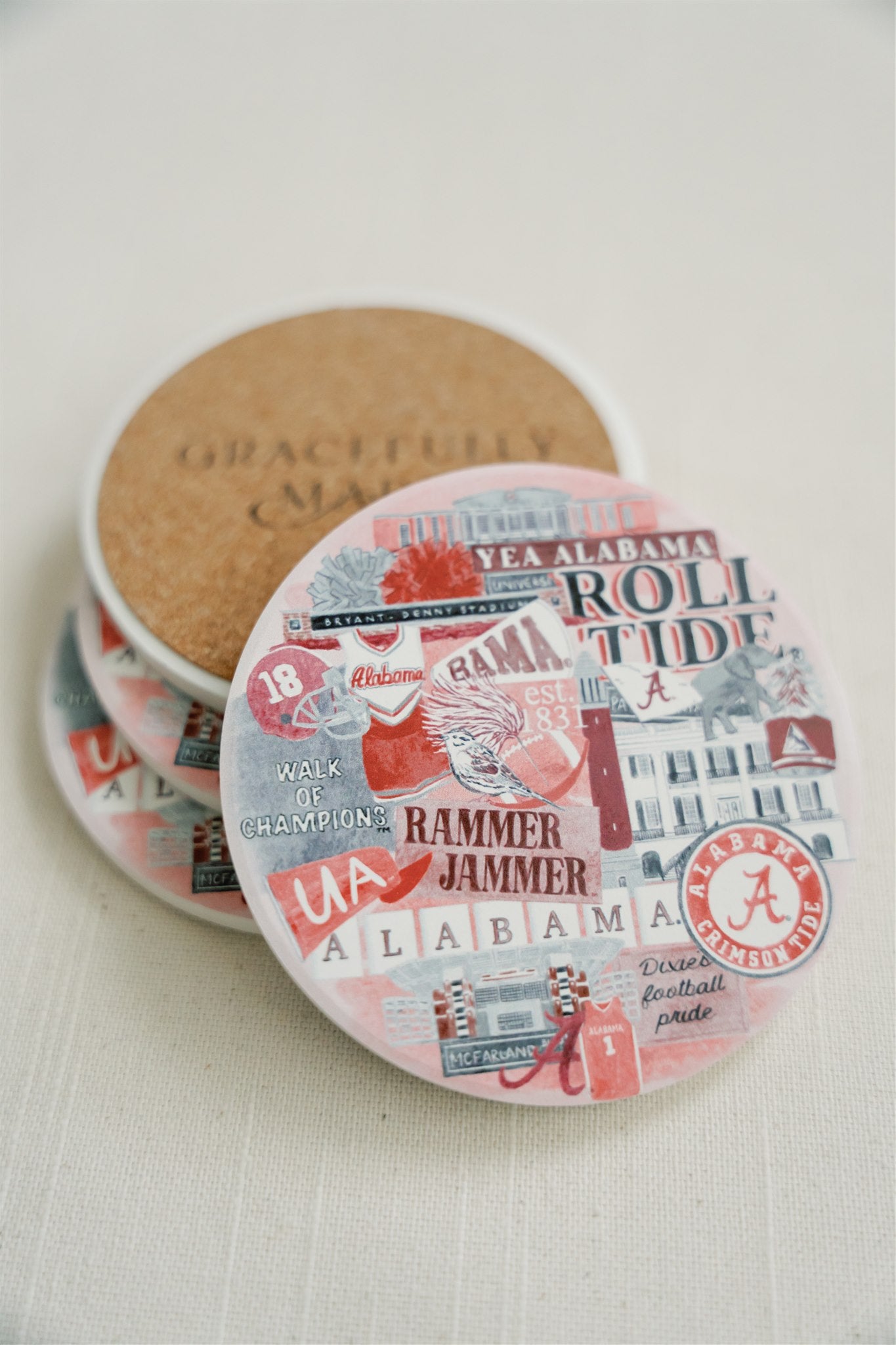 Ceramic coasters featuring a collage of watercolor University of Alabama symbols.