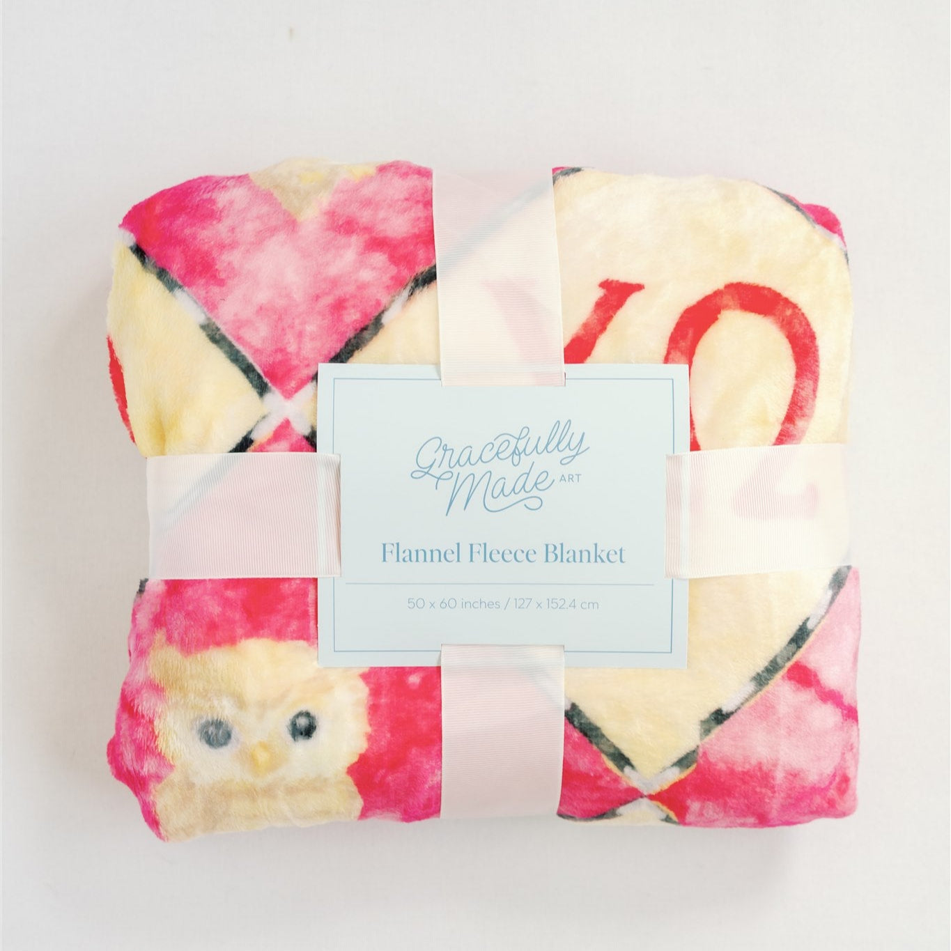 Flannel fleece blanket with a colorful pattern and 'Peacefully Made' label on a light background