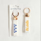 Front and back of a white keychain with Tri Delta Greek letters embroidered on it and Gracefully Made Art branded packaging.