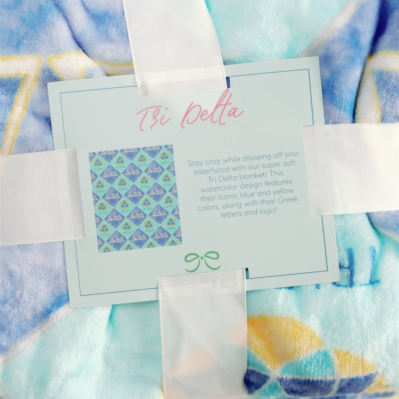 Blanket with Tri Delta watercolor design and text overlay on a matching fabric background