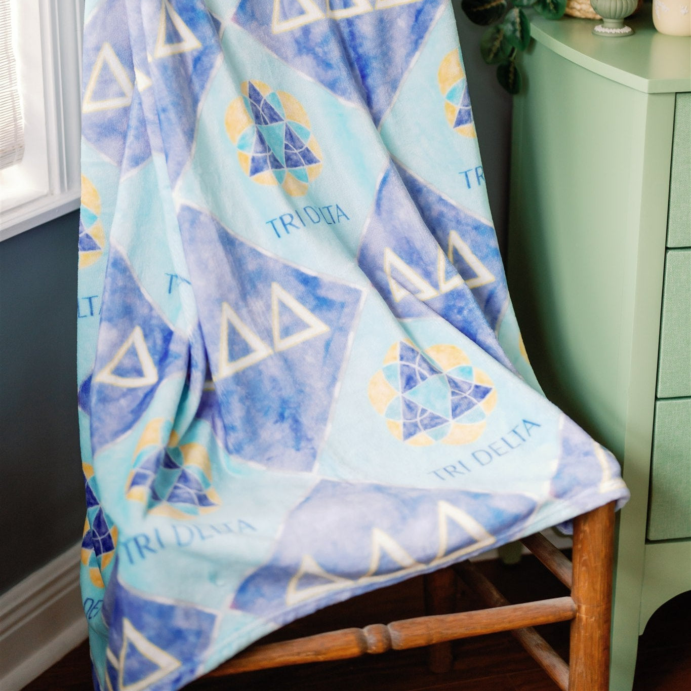 Tri Delta blanket with checkered patterns draped over a chair in a room.