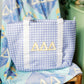 Blue checkered bag with gold Tri Delta Greek letters on a chair.