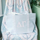 Light blue checkered tote bag with pink Delta Gamma Greek letters on a patterned chair
