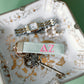 Green keychain with pink Delta Zeta Greek letters embroidered sitting on a jewelry dish.