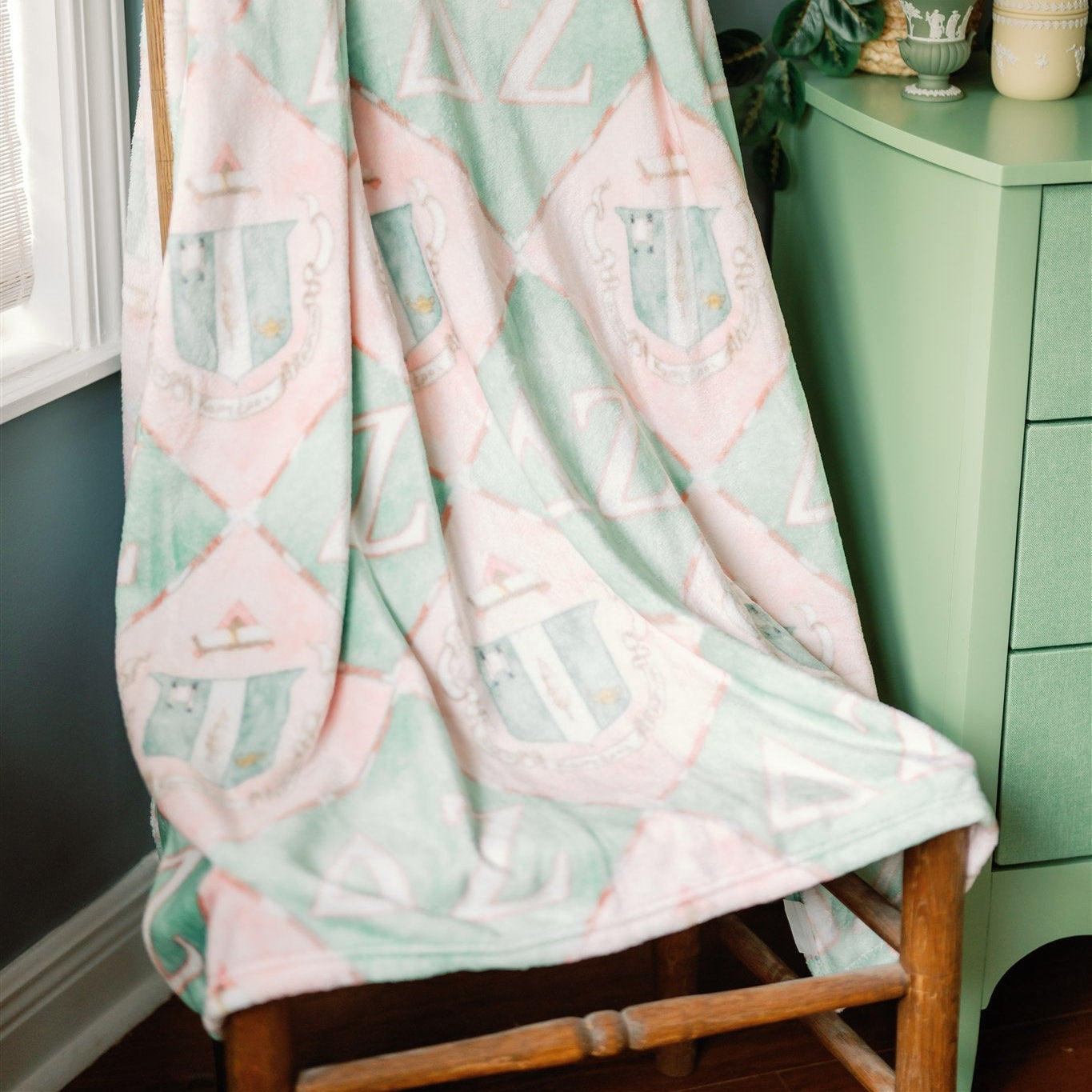 Delta Zeta patterned blanket draped over a wooden chair in a room with green furniture.