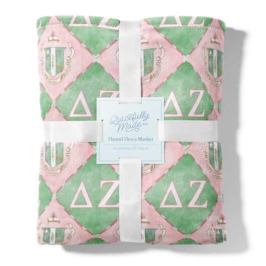Flannel fleece blanket with pink and green pattern and Delta Zeta Greek letters