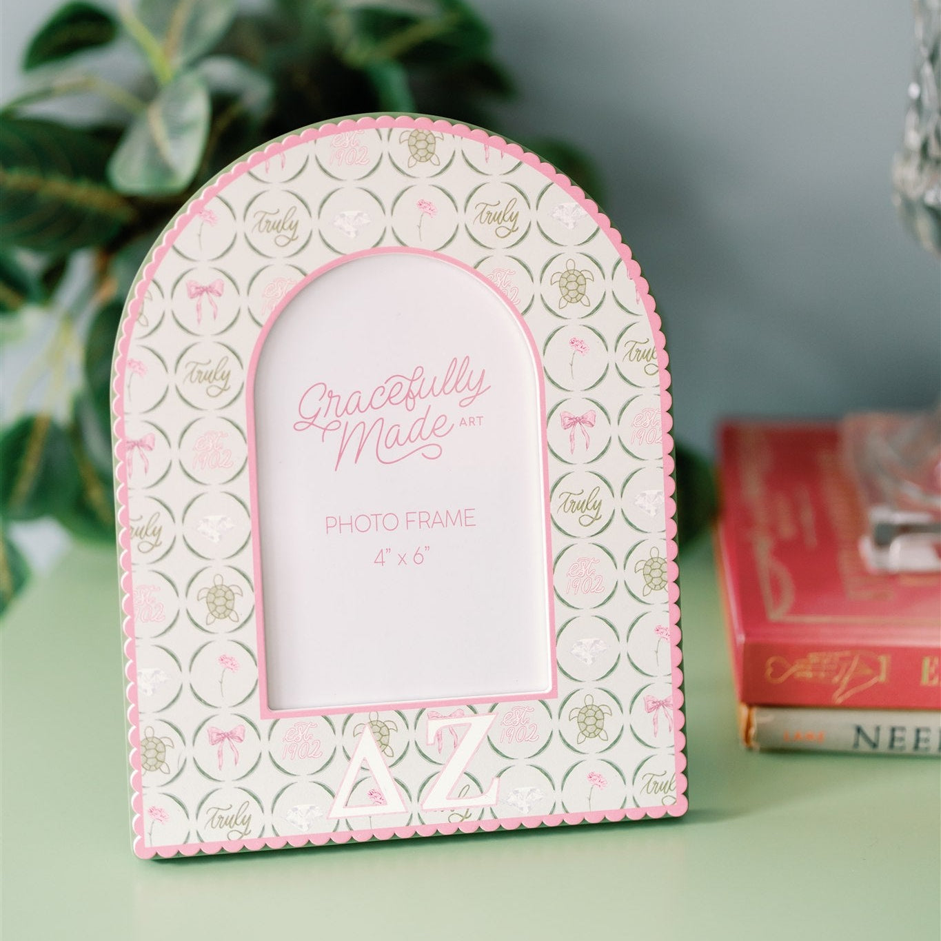 Decorative photo frame with pink and white Delta Zeta design on a green surface