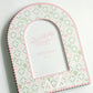 Close up of a pink and green photo frame with Delta Zeta pattern and greek letters on a white background.