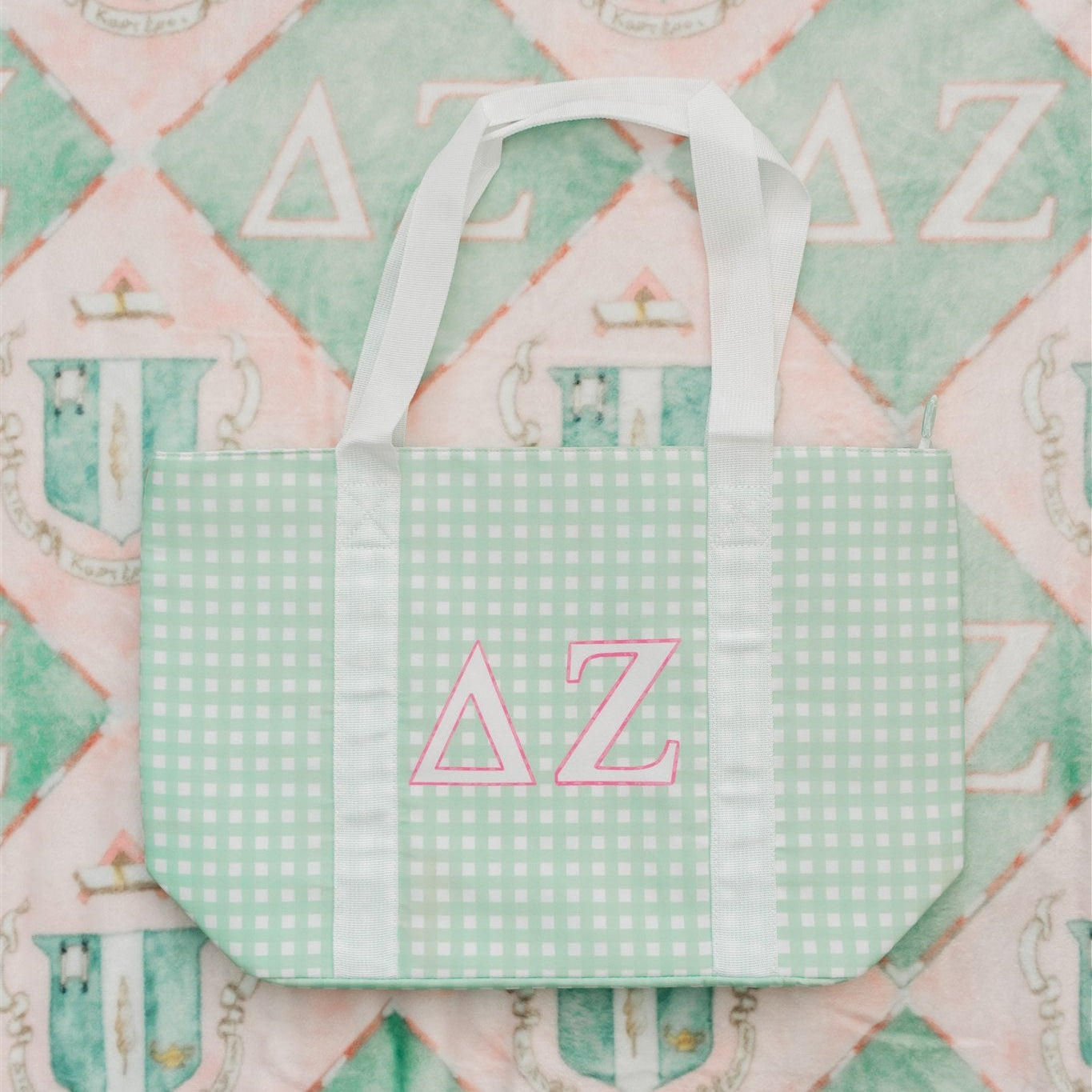 Green checkered tote bag with pink Delta Zeta Greek Letters on a pink and green patterned background