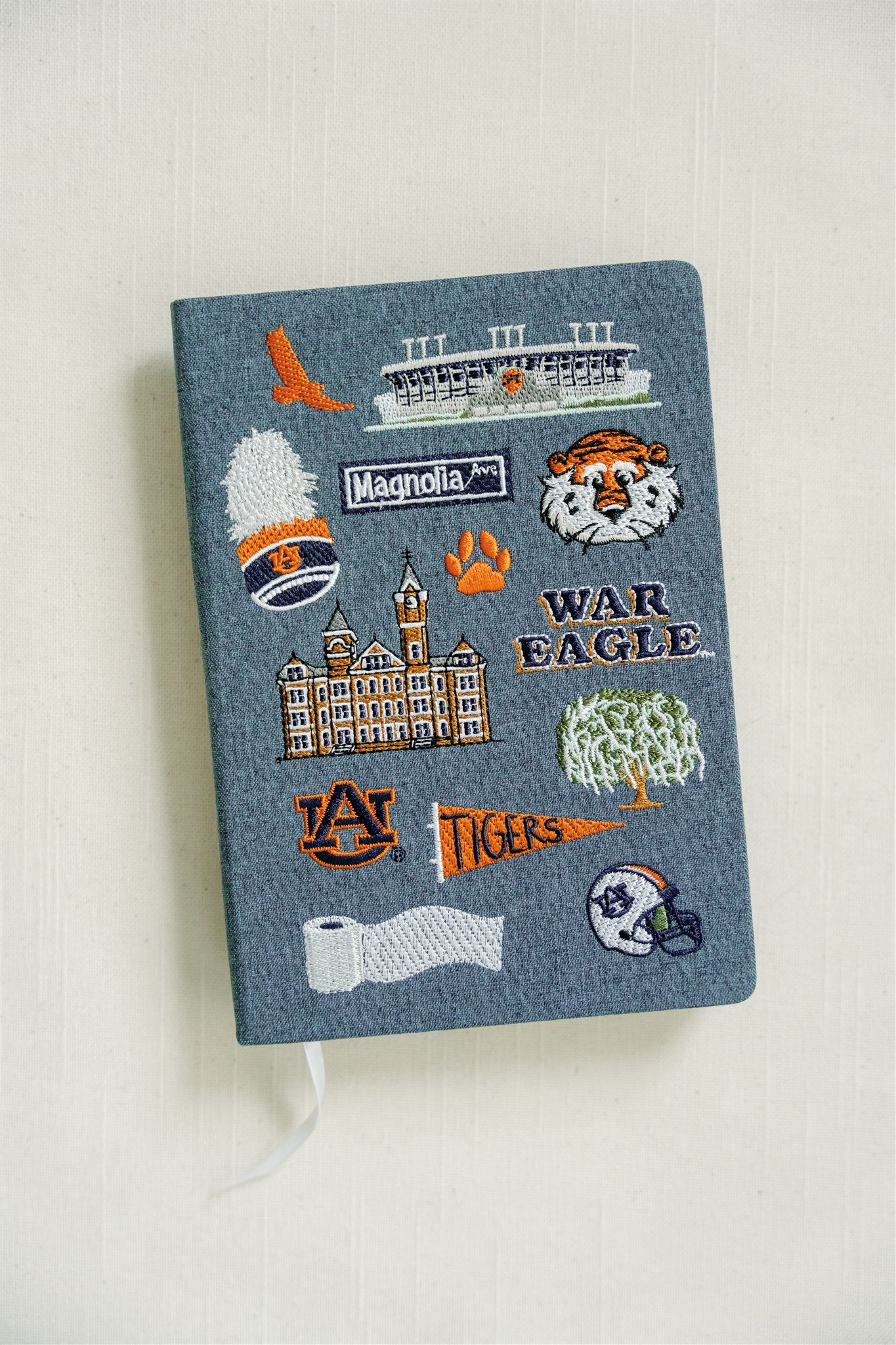 Hardcover navy blue notebook with various Auburn University icons embroidered on the front.