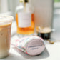 Light pink coffee sleeve with watercolor Taylor Swift inspired symbols.