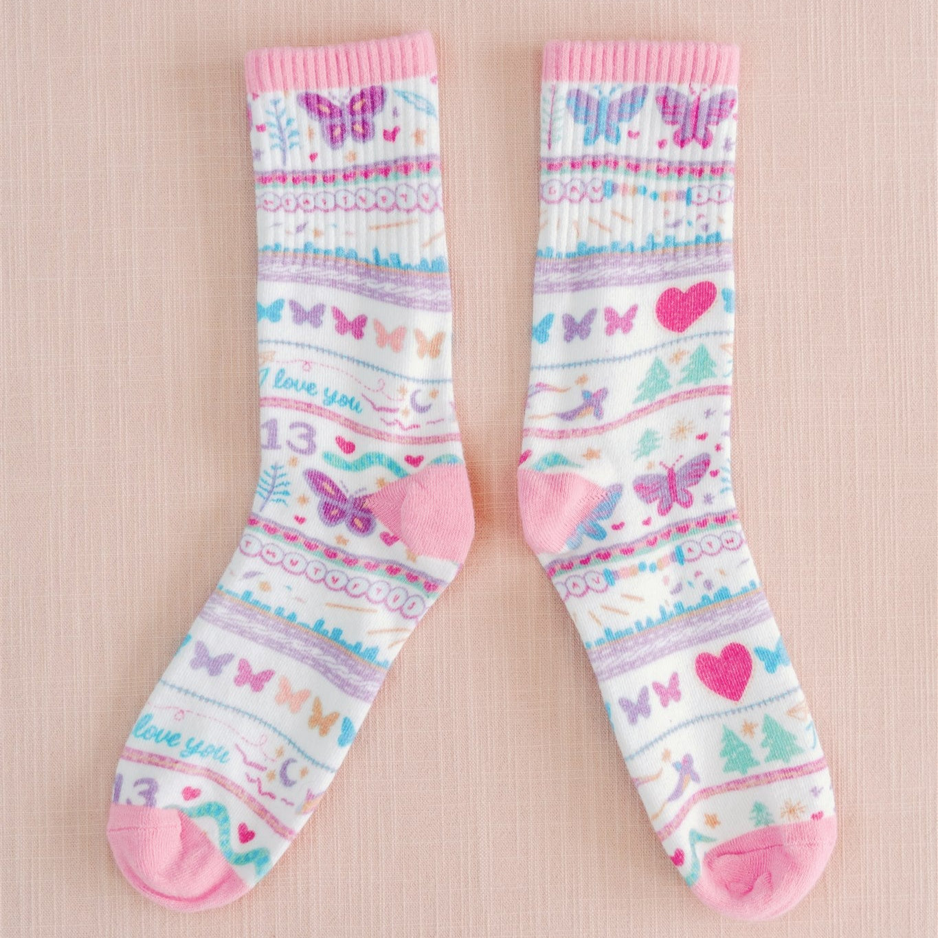 White socks with colorful pattern of butterflies and other Taylor Swift symbols.