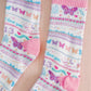 White socks with colorful pattern of butterflies and other Taylor Swift symbols.