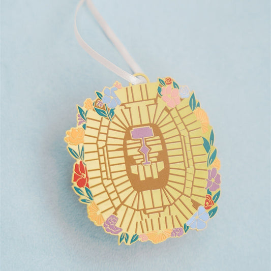 Christmas ornament of the Taylor Swift Eras Tour stadium from an aerial view with flowers around it.
