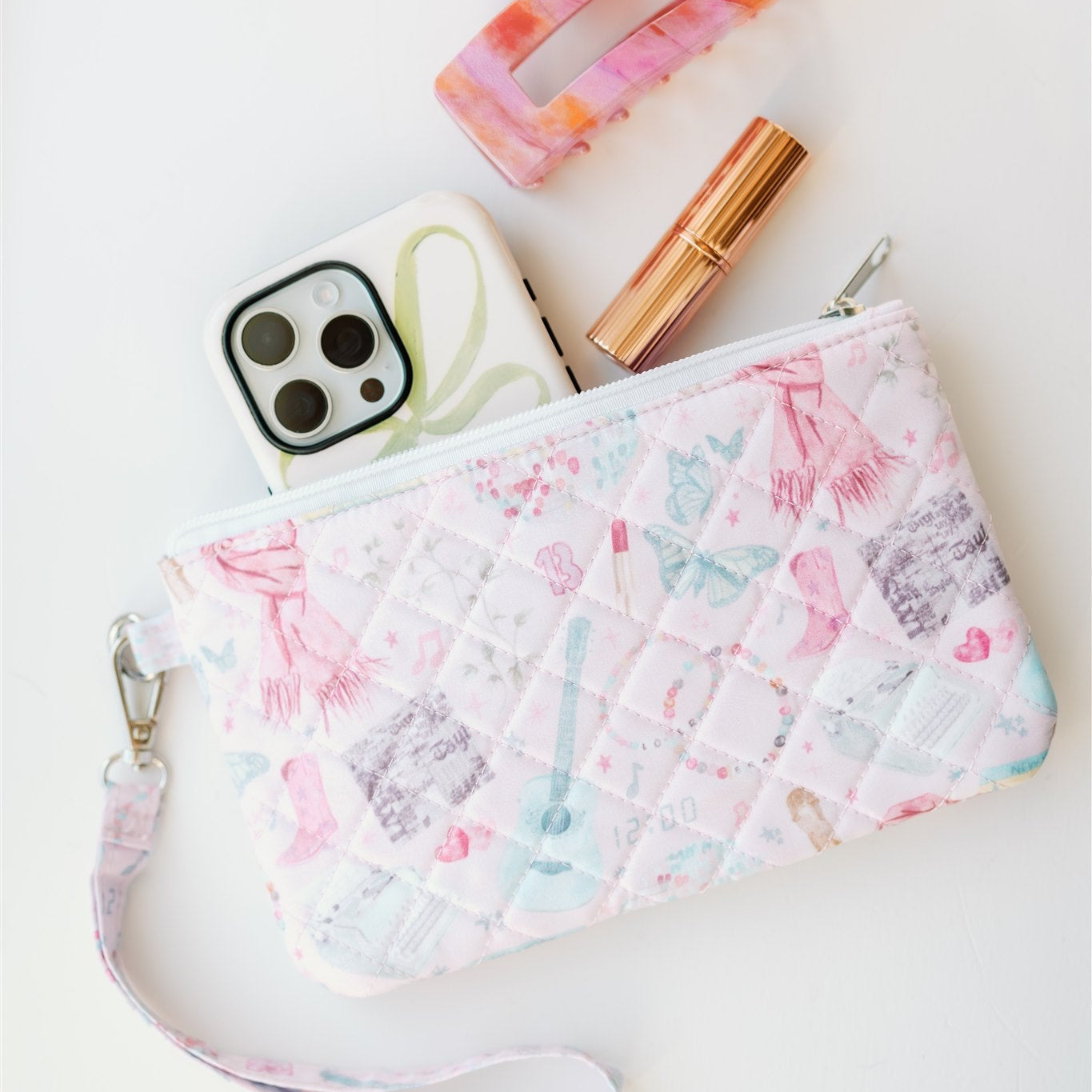 Light pink quilted wristlet with watercolor Taylor Swift symbols as the pattern.