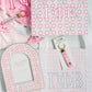 Gamma Phi Beta themed items including a pink keychain, tote bag, and decorative items on a matching pink and white patterned background.
