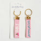 Pink keychains with gold loops and Gamma Phi Beta Greek letters on a white background