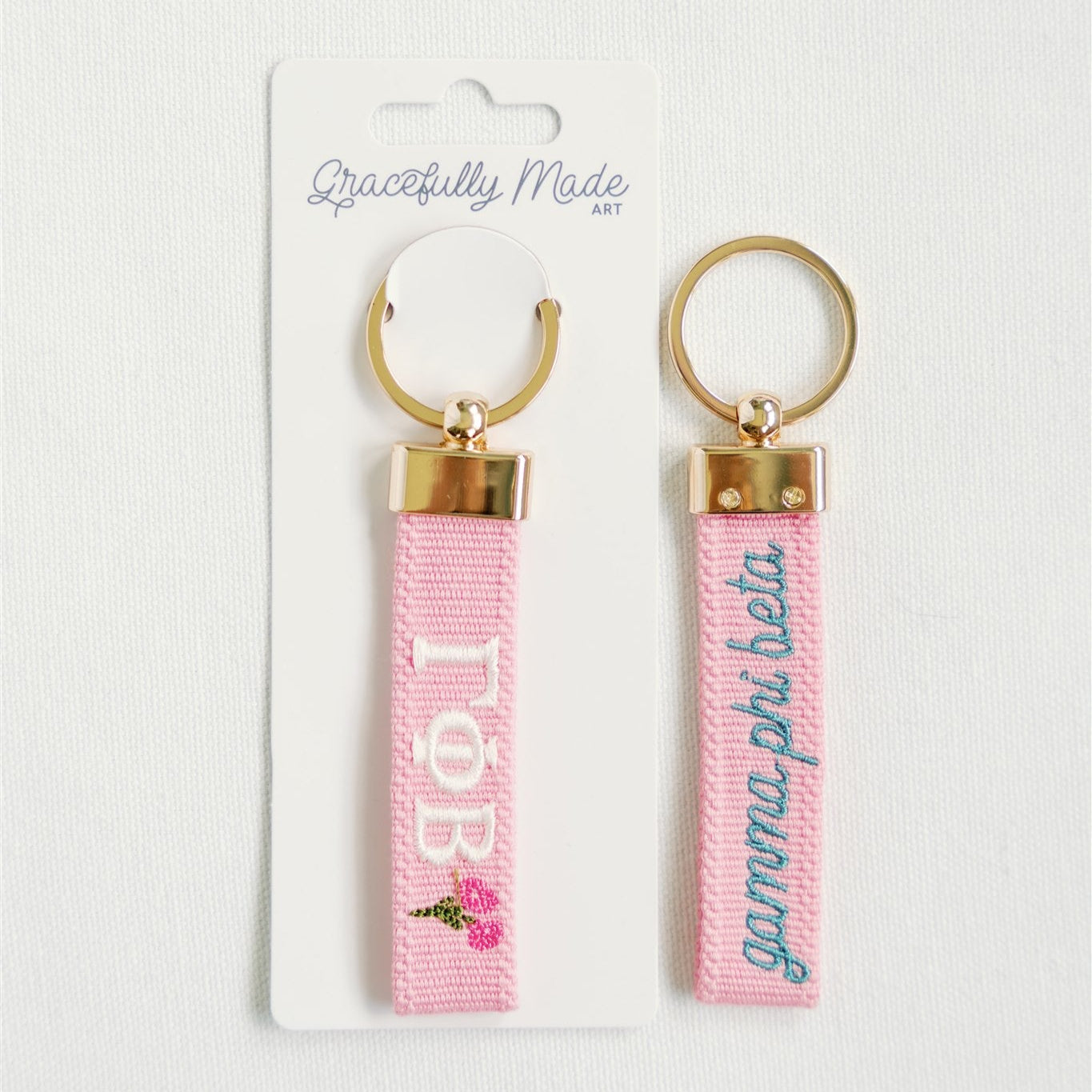 Pink keychains with gold loops and Gamma Phi Beta Greek letters on a white background