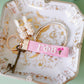 Pink keychain with Gamma Phi Beta Greek letters embroidered on it on a decorative plate