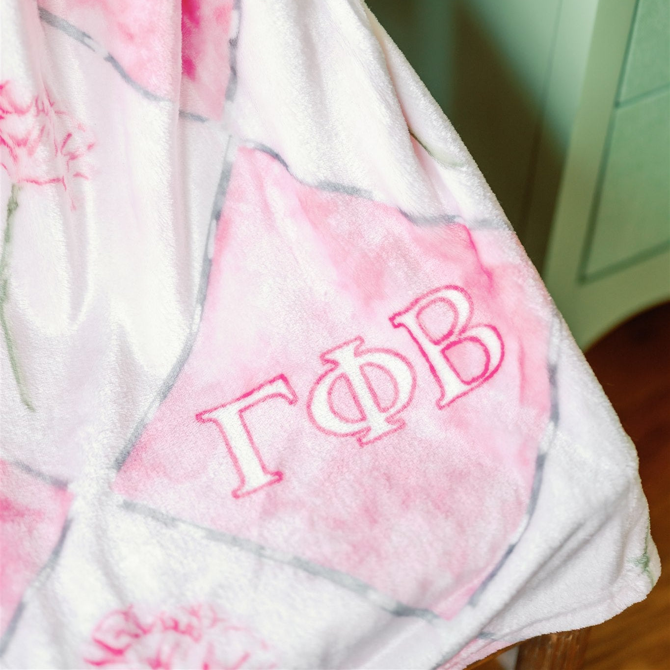 Dark pink and light pink checkered blanket with Gamma Phi Beta Greek letters