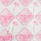Blanket with flowers and Gamma Phi Beta Greek letters on a dark pink and light pink checkered background