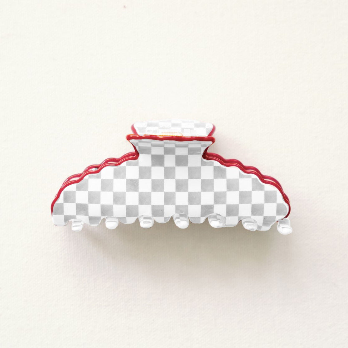 Grey and white checkered hair clip with red scalloped edge.