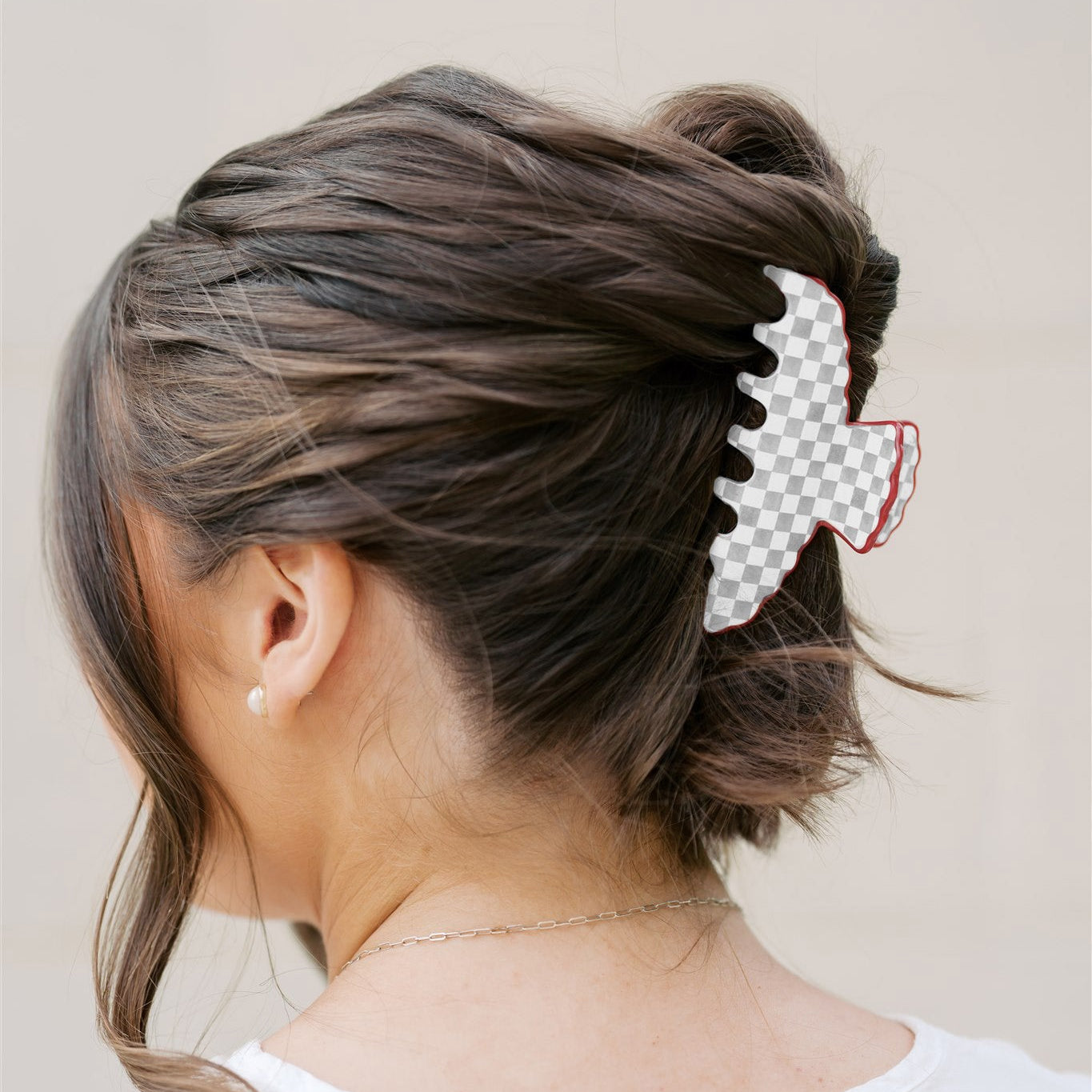 Back view of a person with styled hair featuring a grey and white checkered hair accessory 