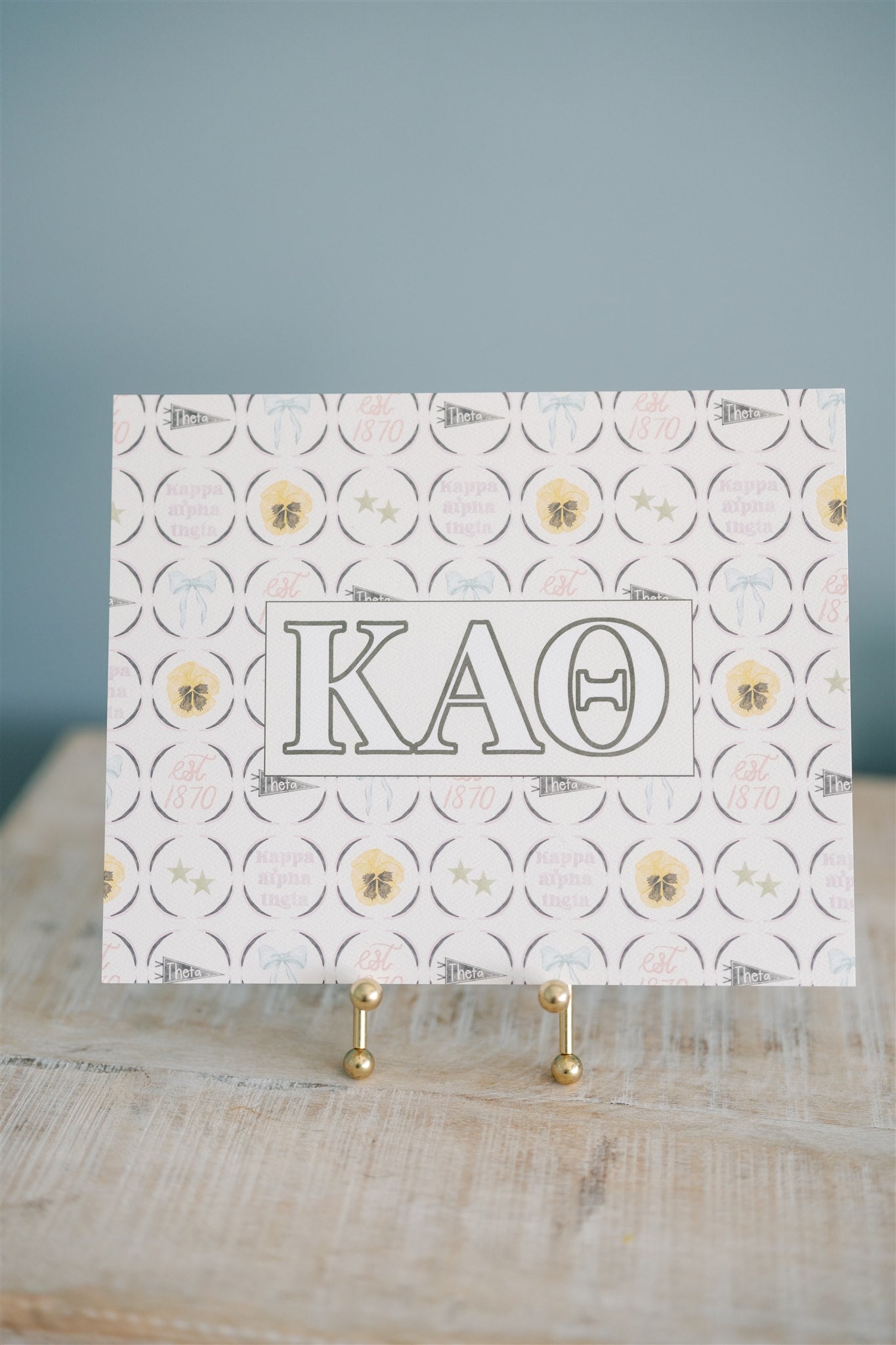 Art print with Kappa Alpha Theta design on a stand against a blue background