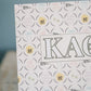 Decorative card with Kappa Alpha Theta Greek letters and circular designs on a stand against a blue background