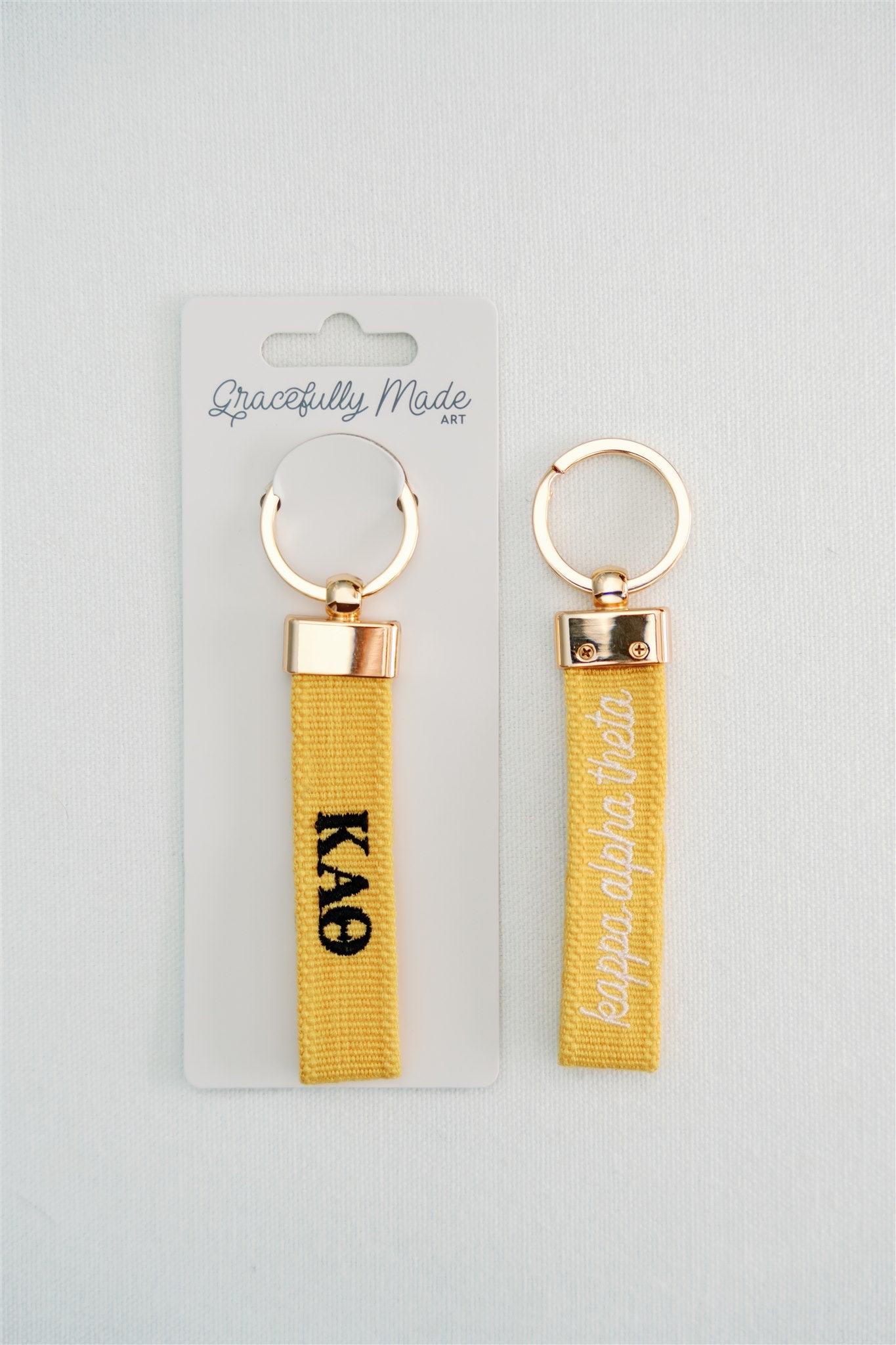 Front and back of a yellow keychain with Kappa Alpha Theta embroidered on it in Gracefully Made Art branded packaging