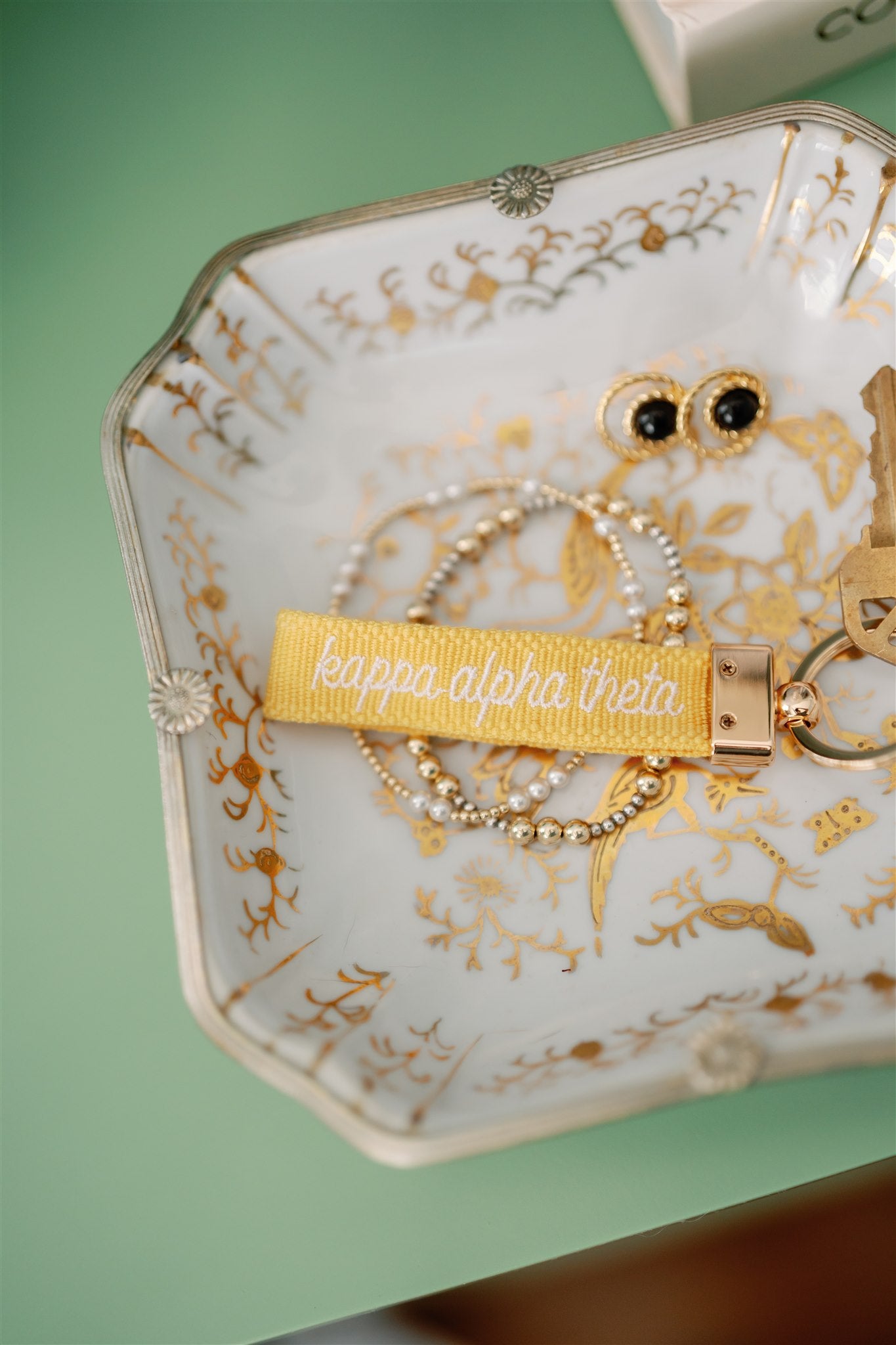 Decorative jewelry dish with a gold keychain with Kappa Alpha Theta embroidered on it